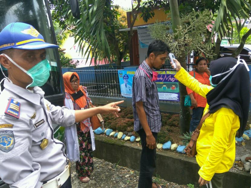 Sejumlah petugas melakukan penyemprotan disinfektan ke angkutan umum dan mengecek suhu tubuh penumpang yang datang dari luar kota, di Kecamatan Kalipucang, Kabupaten Pangandaran, Jumat (27/3). 