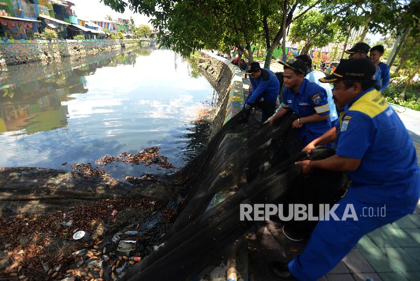 Sejumlah petugas melepaskan kain waring atau jaring yang menutupi Kali Item di kawasan Kemayoran, Jakarta Utara, Kamis (15/11). 