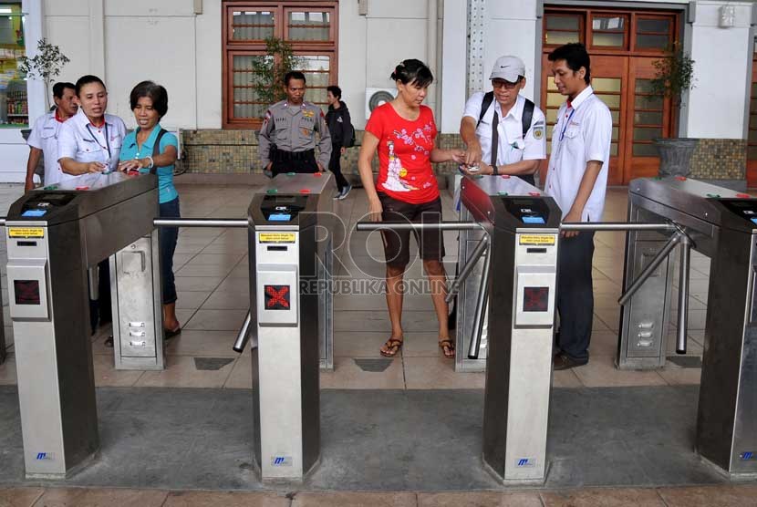   Sejumlah petugas membantu calon penumpang kereta api listrik (KRL) menggunakan tiket elektronik (e-ticketing) di Stasiun Jakarta Kota, Selasa (23/4).    (Republika/Prayogi)