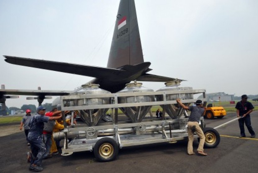 Sejumlah petugas membawa tangki berisi garam untuk dinaikkan ke pesawat Hercules C-130 di Lanud Halim Perdana Kusuma Jakarta, Sabtu (15/3). BPPT bersama TNI AU melakukan modifikasi cuaca dengan menyebar sekitar lima ton garam di Kawasan Riau guna memadamka