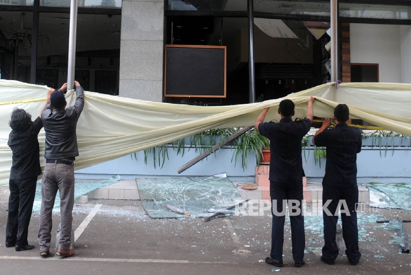 Sejumlah petugas membentangkan plastik untuk menutupi Starbuck Coffee yang terkena ledakan bom di jalan Thamrin, Jakarta, Kamis (14/1). (Republika/Darmawan)