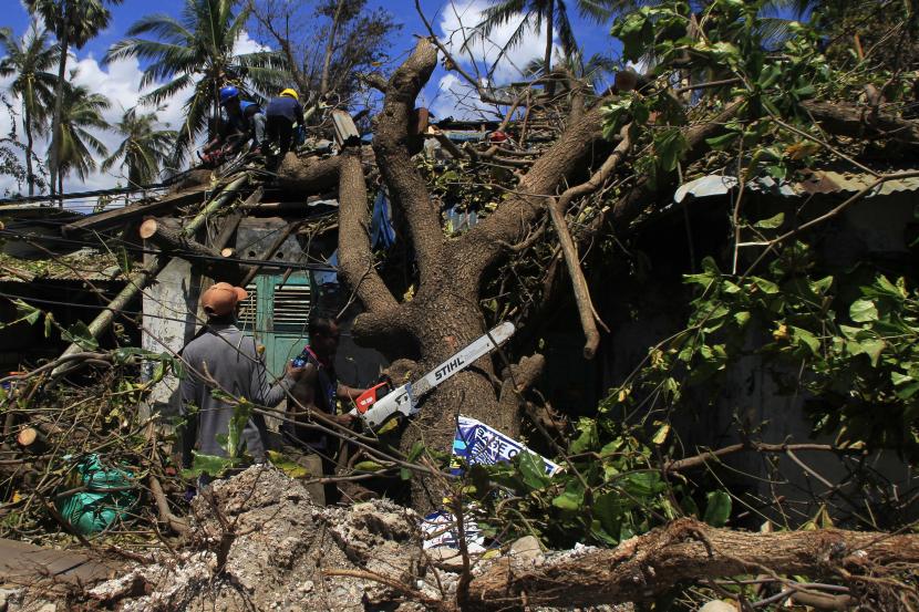 Sejumlah petugas memotong pohon yang tumbang menimpa salah satu rumah karena diterjang gelombang kencang akibat badai Siklon tropis Seroja di Kota Kupang, NTT, Kamis (8/4/2021). Badan Penanggulangan Bencana Daerah (BPBD) Kota Kupang mencatat sebanyak 1.264 rumah mengalami rusak berat, satu orang meninggal dunia dan tujuh orang luka berat dampak dari angin kencang pada Minggu (4/4). 