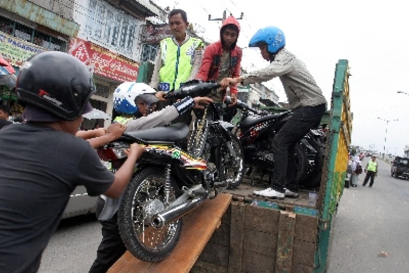 Sejumlah petugas mengangkut sepeda motor milik siswa yang tidak memiliki surat kendaraan ke dalam bak truk saat razia geng motor.