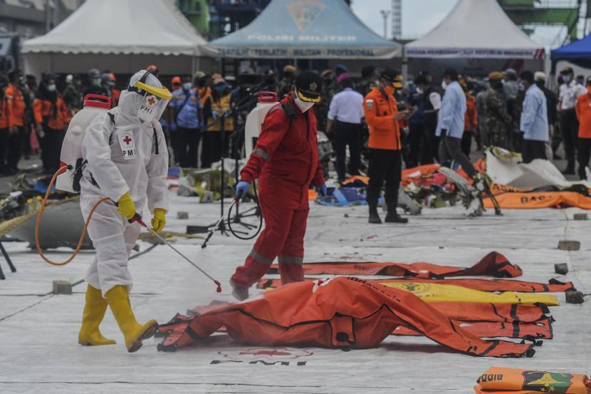 Sejumlah petugas menyemprotkan disinfektan kantong jenazah korban jatuhnya pesawat Sriwijaya Air nomor penerbangan SJ182 di Dermaga JICT II, Jakarta.