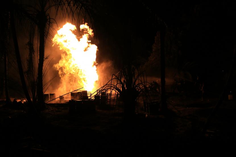 Sejumlah petugas pemadam kebakaran berusaha memadamkan api di sumur minyak ilegal yang berada di kawasan pemukiman penduduk Desa Mata Ie, Kecamatan Ranto Peureulak, Aceh Timur, Sabtu (12/3/2022). Kebakaran di salah satu sumur minyak ilegal pada Jumat (11/3/2022) sekitar pukul 23.30 WIB tersebut mengakibatkan tiga warga mengalami luka bakar serius. 
