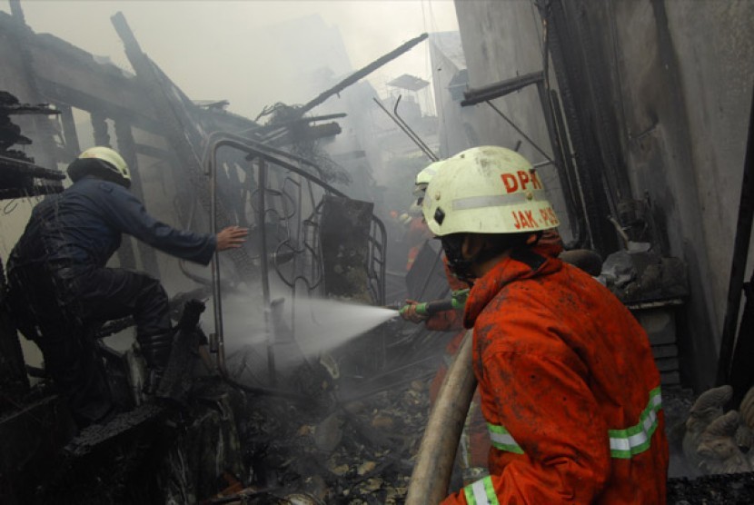 Sejumlah petugas pemadam kebakaran berusaha memadamkan sisa api yang masih menyala ketika terjadi kebakaran di kawasan Jalan Kartini, Jakarta, Senin (27/8).