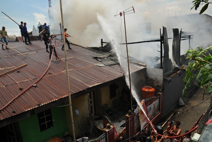 Sejumlah petugas pemadam kebakaran dibantu masyarakat berusaha memadamkan api yang melanda kawasan padat perumahan di Rappokalling Timur, Makassar, Sulsel, Rabu (28/3). Api yang di duga akibat hubungan arus pendek listrik itu menyebabkan Ttga rumah habis t