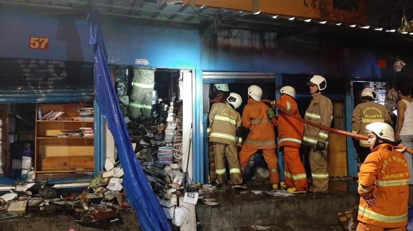 Sejumlah petugas pemadam menyemprotkan air ke tumpukan buku yang ada dalam kios di Terminal Senen, Jakarta Pusat, Selasa (18/5) malam. Sebanyak 12 kios buku hangus terbakar dalam insiden ini.  