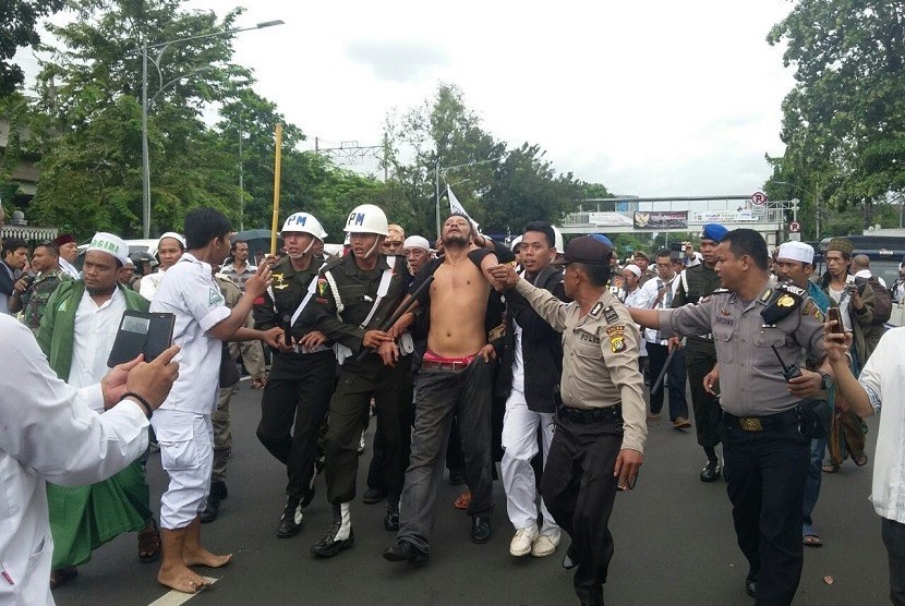 Sejumlah petugas Polisi Militer (PM) mengamankan seorang pria  diduga mabok di pintu timur Stasiun Gambir, Jakarta Pusat, usai berlangsungnya aksi damai 212 pada hari ini, Jumat (2/12). 