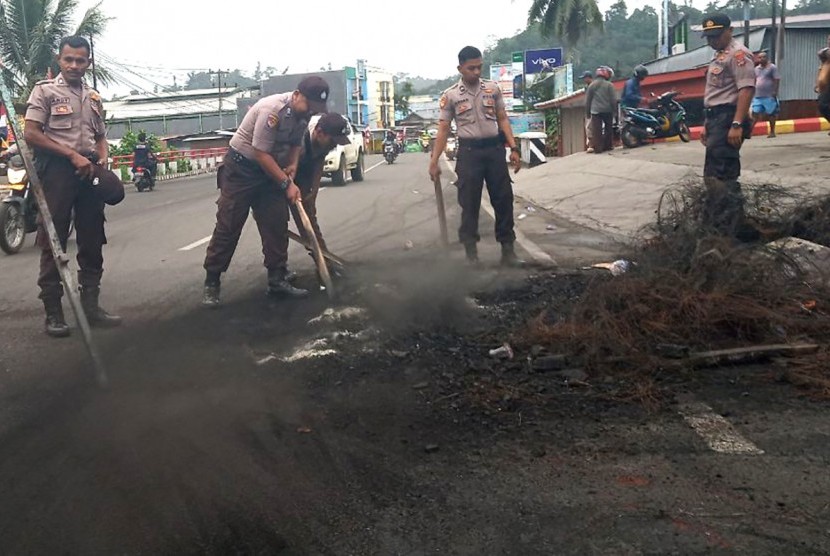 Sejumlah polisi membersihkan sisa kerusuhan di salah satu ruas jalan di Manokwari, Papua Barat, Selasa (20/8/2019).