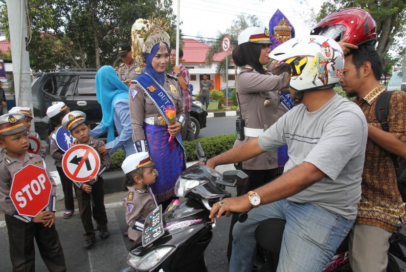Sejumlah polisi wanita (polwan) memakaikan helm kepada pengendara motor (Ilustrasi).
