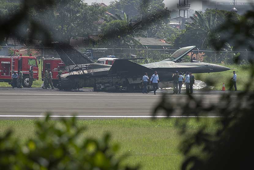 Sejumlah prajurit TNI AU berjaga di dekat badan pesawat tempur F16 yang terbakar di ujung landasan pacu Pangkalan Udara Halim Perdanakusuma, Jakarta Timur, Kamis (16/4).    (Antara/Rosa Panggabean)