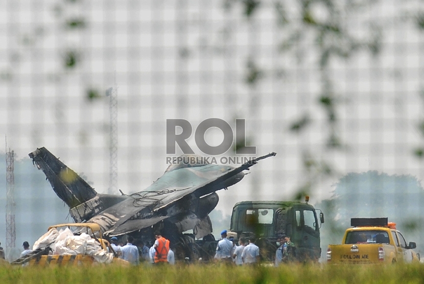 Sejumlah prajurit TNI AU melakukan proses evakuasi badan pesawat tempur F16 yang terbakar di ujung landasan pacu Pangkalan Udara Halim Perdanakusuma, Jakarta Timur, Kamis (16/4). (Republika/Edwin Dwi Putranto)