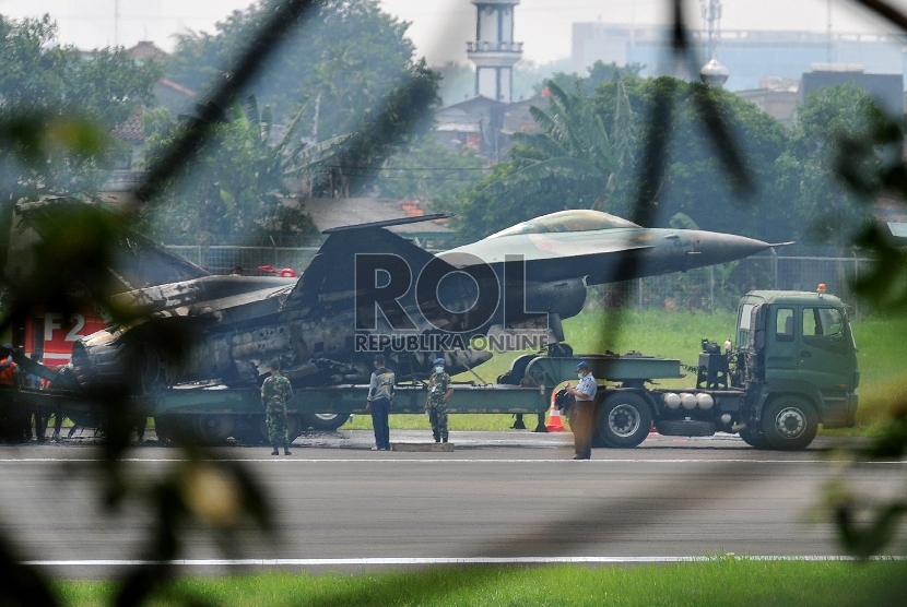 Sejumlah prajurit TNI AU melakukan proses evakuasi badan pesawat tempur F16 yang terbakar di ujung landasan pacu Pangkalan Udara Halim Perdanakusuma, Jakarta Timur, Kamis (16/4). (Republika/Edwin Dwi Putranto)