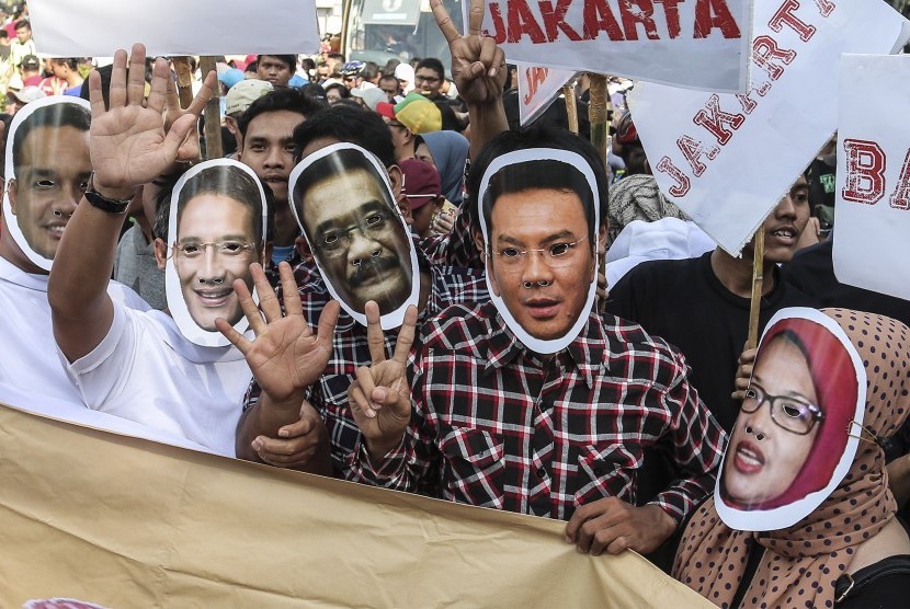 Sejumlah relawan ketiga pasangan calon gubernur dan wakil gubernur DKI Jakarta menggunakan topeng ketiga paslon pada aksi kampanye damai di Kawasan Bunderan Hotel Indonesia, Jakarta, Jumat (28/10). 