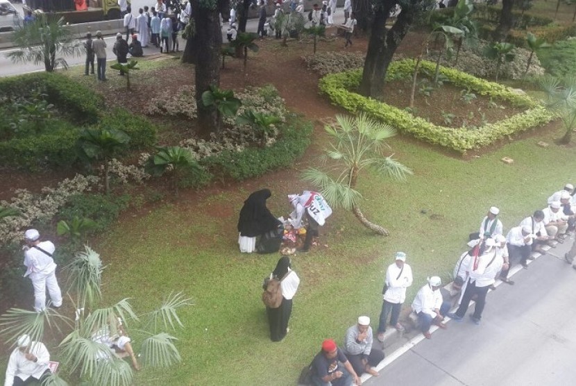 Sejumlah relawan memunguti sisa sampah di taman kota saat aksi damai Bela Islam, Jumat (4/11).