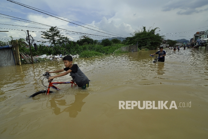 Sejumlah remaja menerobos banjir yang merendam di Jalan Raya Banjaran di Kelurahan Andir, Kecamatan Baleendah, Kabupaten Bandung, Rabu (8/3). 