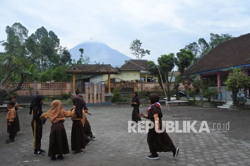 Sejumlah siswa bermain di halaman SDN Supiturang 2 dengan latar belakang Gunung Semeru di Desa Supiturang, Pronojiwo, Lumajang, Jawa Timur, Sabtu (12/2/2022). Aktivitas Gunung Semeru Didominasi Letusan