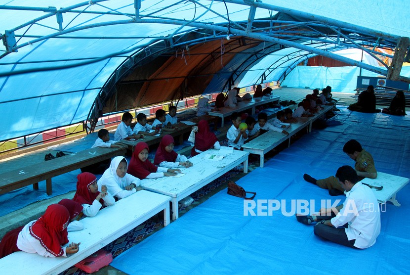 Sejumlah siswa dan siswi sekolah dasar mengikuti proses belajar di tenda pengungsian sementara di lapangan upacara Merdeka, Kabupaten Mamasa, Sulawesi Barat, Senin (26/11/2018). 