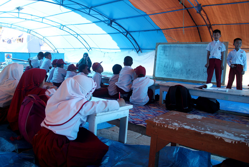 Sejumlah siswa dan siswi sekolah dasar mengikuti proses belajar di tenda pengungsian sementara di lapangan upacara Merdeka, Kabupaten Mamasa, Sulawesi Barat, Senin (26/11). 