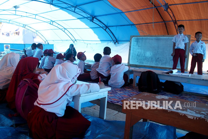 Sejumlah siswa dan siswi sekolah dasar mengikuti proses belajar di tenda pengungsian sementara di lapangan upacara Merdeka, Kabupaten Mamasa, Sulawesi Barat, Senin (26/11/2018). 