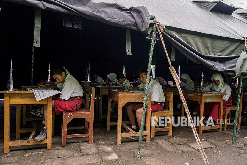 Sejumlah siswa kelas enam sekolah dasar, mengikuti Ujian Sekolah (US) di tenda darurat di halaman sekolah SD Negeri 1 Kasinoman, Kalibening, Banjarnegara, Jateng, Senin (23/4). 