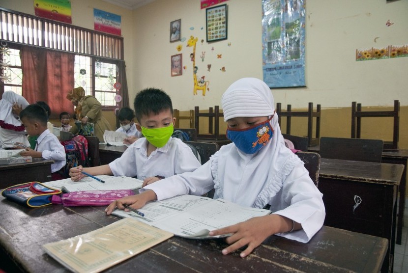 Sejumlah siswa kelas I SDN 15 mengenakan masker saat hari pertama sekolah kembali aktif di Kota Pekanbaru, Riau, Senin (5/10). 