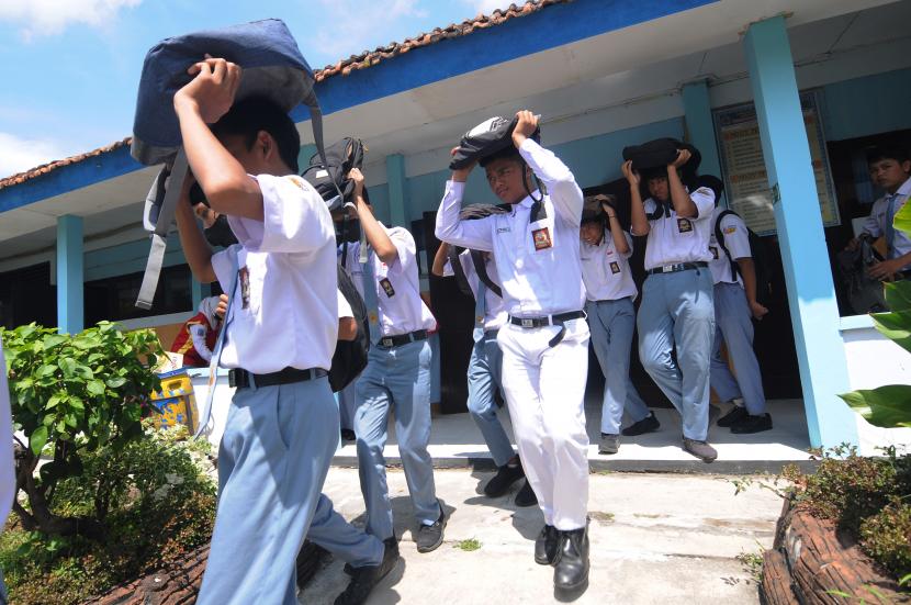 Sejumlah siswa melindungi kepala mereka menggunakan tas saat simulasi kesiapsiagaan kebencanaan. (ilustrasi)