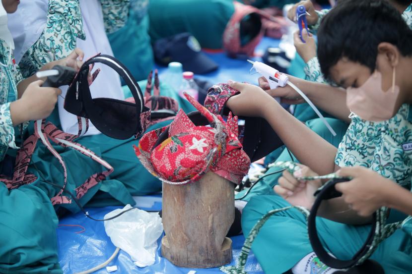 Sejumlah siswa membuat udeng pacul gowang di SMP Negeri 4 Sidoarjo, Jawa Timur, Rabu (31/8/2022). Kegiatan yang diikuti 1300 orang dan terdiri dari siswa, GTK, komite sekolah, orang tua siswa dan tokoh masyarakat tersebut untuk mengenakanl dan mencintai budaya khas Sidoarjo. 
