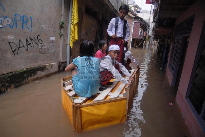   Sejumlah siswa menggunakan sampan untuk melintasi banjir yang merendam rumah mereka di Kampung Pulo, Jakarta Timur, Jumat (6/12).     (Republika/Rakhmawaty La'lang)