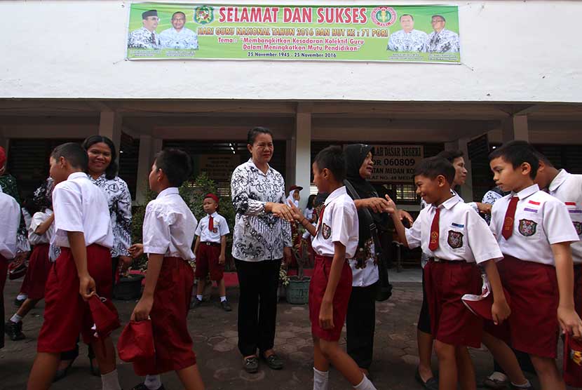 Sejumlah siswa menyalami guru mereka seusai mengikuti upacara di Sekolah Dasar Negeri 060813 Medan, Sumatera Utara, Jumat (25/11). 