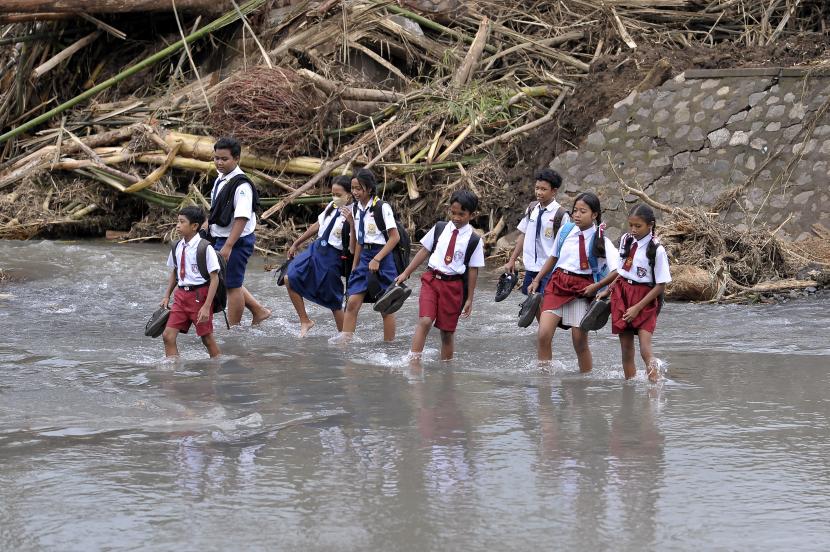 Sejumlah siswa menyeberangi sungai saat berangkat ke sekolah pascabanjir bandang di Dusun Sekar Kejula Kelod, Desa Yehembang Kauh, Jembrana, Bali, Selasa (25/10/2022).