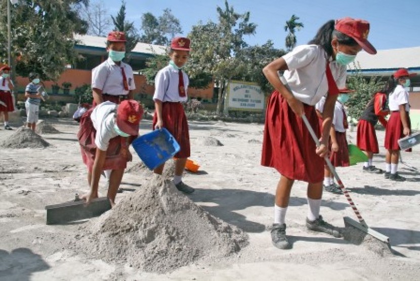 Sejumlah siswa SD membersihkan halaman sekolah pasca erupsi Gunung Sinabung, di Desa Payung, Karo, Sumatra Utara, Selasa (20/2). 