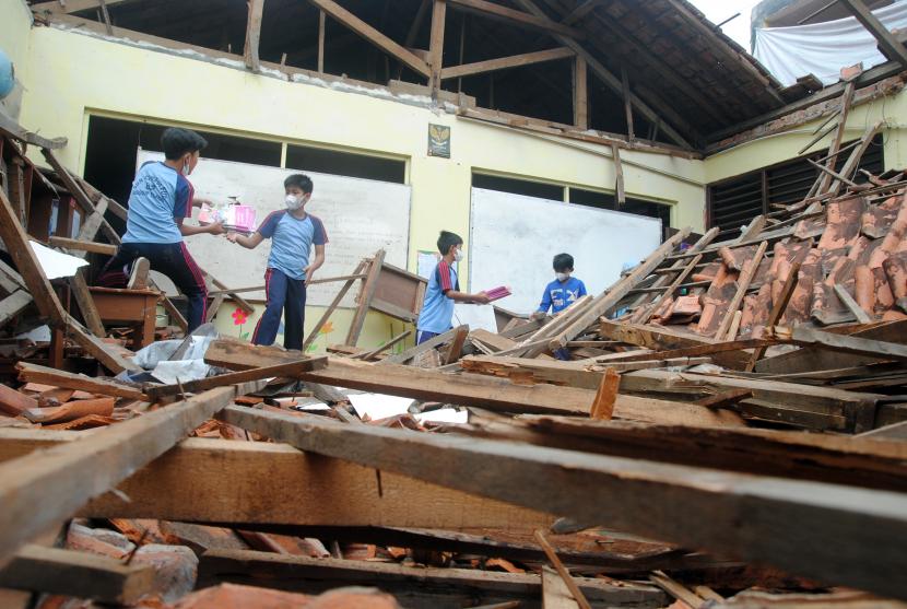 Sejumlah siswa SD mengangkat buku pelajaran diantara puing atap sekolah yang ambruk. (Ilustrasi)
