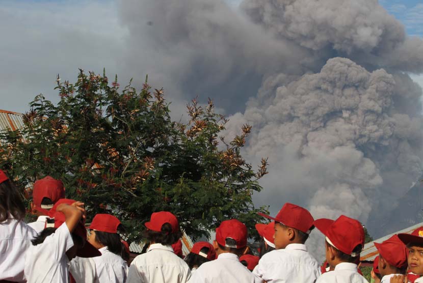 Sejumlah siswa SD Negeri 040482 mengikuti upacara bendera pada hari pertama masuk sekolah, ketika terjadi erupsi Gunung Sinabung, di Desa Gajah, Karo, Sumut, Senin (6/1).   (Antara/Irsan Mulyadi)