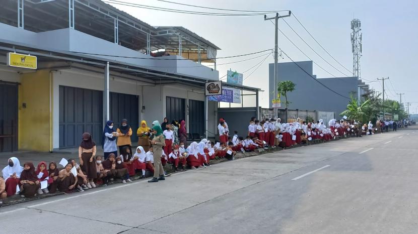 Sejumlah siswa SD, orang tua siswa, guru, masyarakat di Soreang, Kabupaten Bandung tengah menunggu rombongan yang membawa jenazah Eril putra Gubernur Jabar Ridwan Kamil di akses keluar tol Soroja menuju ke pemakaman di Cimaung, Kabupaten Bandung, Senin (13/6/2022). Terdapat beberapa titik lokasi warga yang menunggu ingin menyambut rombongan. 