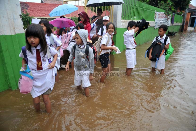   Sejumlah siswa SD terpaksa pulang sekolah melintasi banjir yang terjadi di kawasan Kampung Melayu Kecil, Jakarta,Senin (22/7).   (Republika/Prayogi)