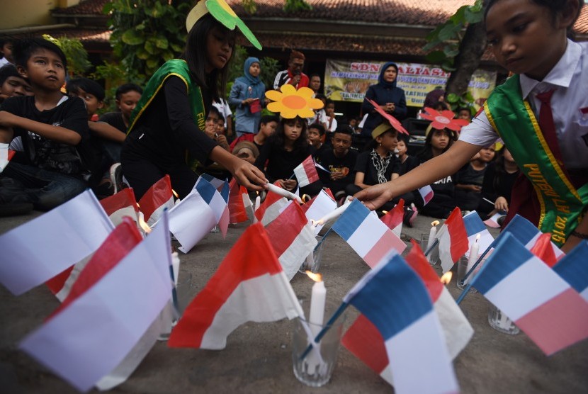 Sejumlah siswa SDN Kaliasin I Surabaya menyalakan lilin ketika menggelar aksi 'Pray for Paris' di halaman sekolahnya, Surabaya, Jawa Timur, Selasa (17/11).