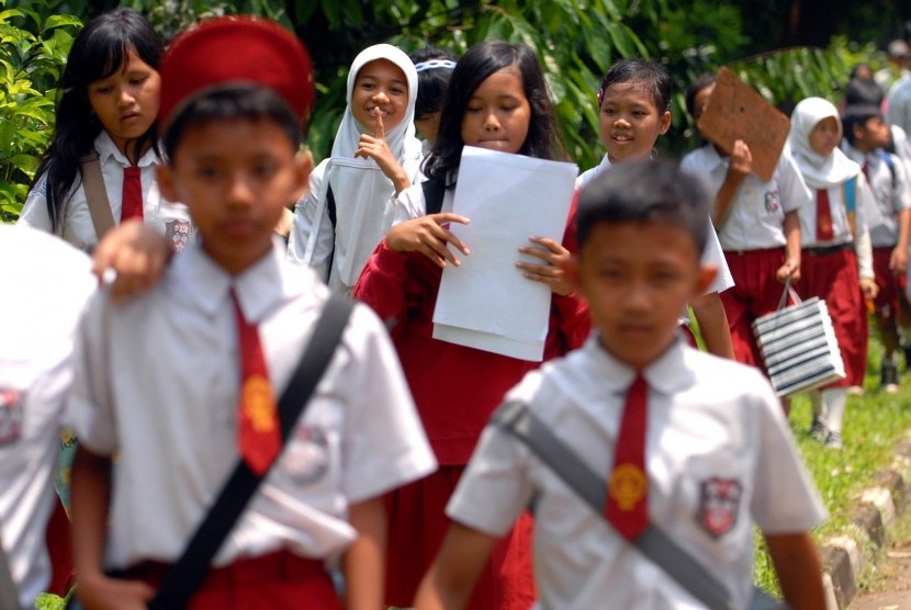 Sejumlah siswa sekolah dasar (SD) berjalan sambil membawa soal-soal setelah pelaksanaan uji coba ujian nasional (ilustrasi).