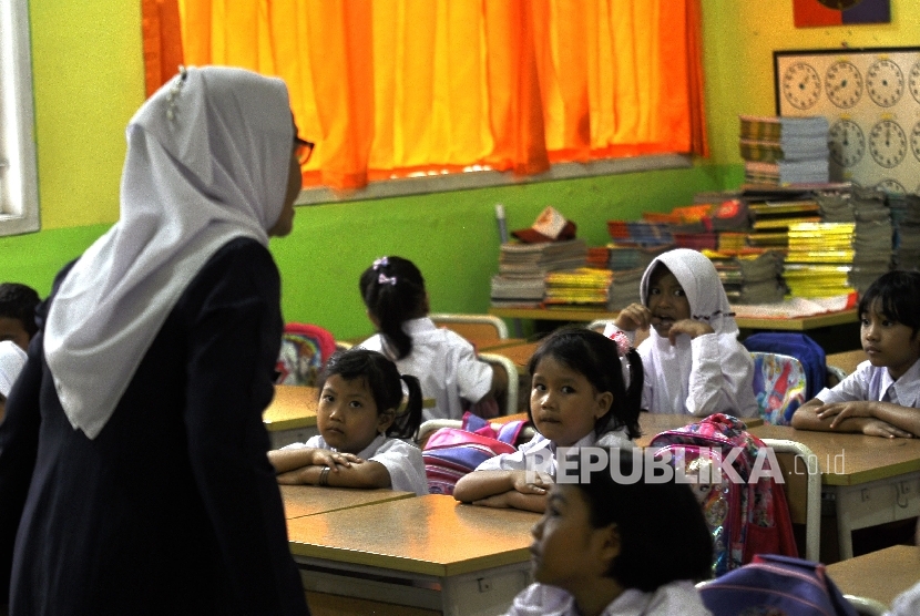 Sejumlah siswa-siswi murid baru kelas 1 memperhatikan gurunya saat memberi arahan pada hari pertama masuk sekolah di Sekolah Dasar Negeri (SDN) Pejaten Barat 10 Pagi, Jakarta Selatan, Senin (10/7).