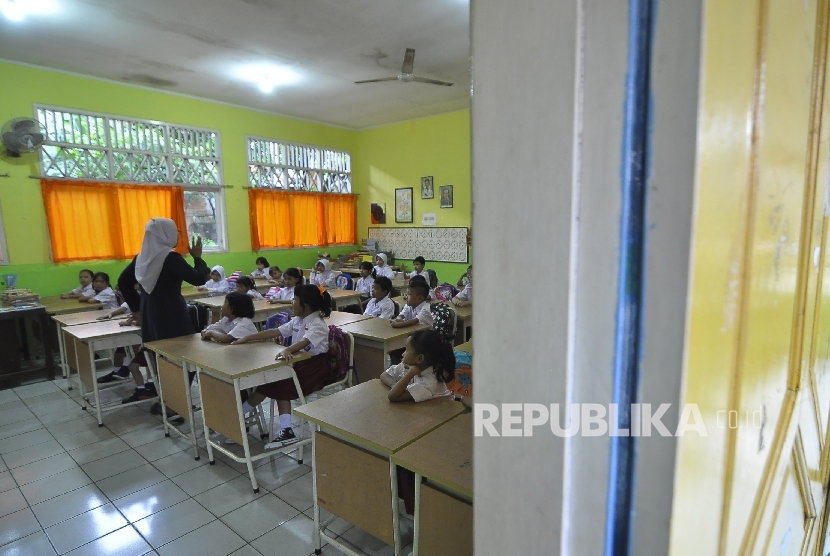 Sejumlah siswa-siswi murid baru kelas 1 memperhatikan gurunya saat memberi arahan pada hari pertama masuk sekolah di Sekolah Dasar Negeri (SDN) Pejaten Barat 10 Pagi, Jakarta Selatan, Senin (10/7).