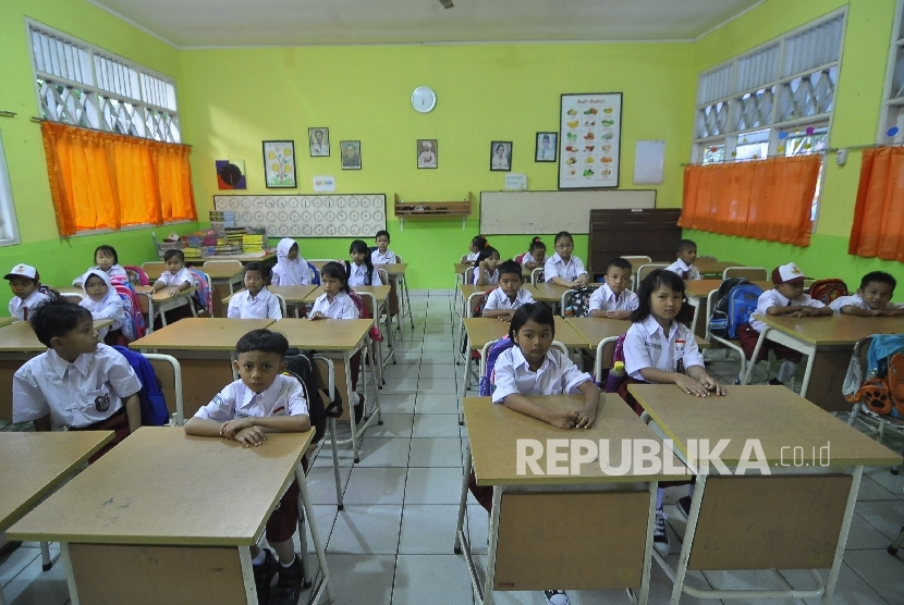 Sejumlah siswa-siswi murid baru kelas 1 memperhatikan gurunya saat memberi arahan pada hari pertama masuk sekolah di Sekolah Dasar Negeri (SDN) Pejaten Barat 10 Pagi, Jakarta Selatan, Senin (10/7).