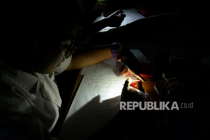 Sejumlah siswa SMAN 48 Jakarta mengikuti kegiatan belajar mengajar dengan bantuan lampu senter, Selasa (22/11).