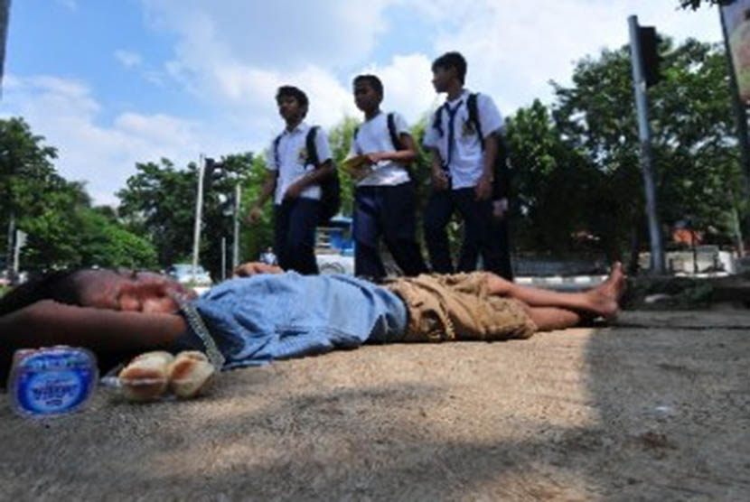 Sejumlah siswa SMP berjalan melintasi seorang anak gelandangan (putus sekolah) yang tertidur di kawasan Kebayoran Baru, Jakarta. 