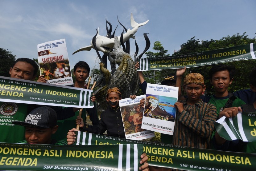 Sejumlah siswa SMP Muhammadiyah 1 Kapasan Surabaya membentangkan poster di depan patung Patung Suro dan Boyo di Kebun Binatang Surabaya saat aksi peringati Hari Dongeng Internasional, Surabaya, Jawa Timur, Jumat (18/3).