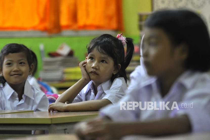 Sejumlah siswi murid baru kelas 1 memperhatikan gurunya saat memberi arahan pada hari pertama masuk sekolah di Sekolah Dasar Negeri (SDN) Pejaten Barat 10 Pagi, Jakarta Selatan, Senin (10/7).