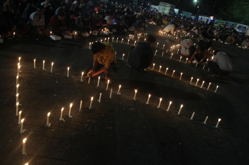 Sejumlah suporter Arema FC (Aremania) menyalakan lilin sebelum mengikuti doa bersama di depan patung singa Stadion Kanjuruhan, Malang, Jawa Timur, Selasa (4/10/2022). Doa bersama untuk para korban tragedi Kanjuruhan pada hari ke-3 tersebut semakin banyak diikuti warga setempat maupun suporter Arema FC dari berbagai daerah. 