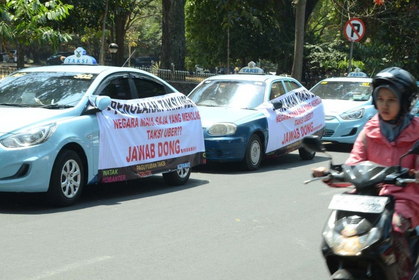 Sejumlah taxi memasang sepanduk menolak keberadaan Taksi Uber bertepatan dengan 'Seminar Fenomena Moda Transportasi Baru Kota Bandung di Era Digital' di Aula Barat, Kampus ITB, Kota Bandung, Senin (24/8)