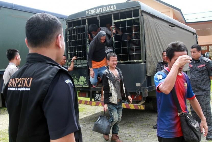  Sejumlah Tenaga Kerja Indonesia (TKI) turun dari truk tahanan imigrasi Malaysia saat tiba di perbatasan Entikong, Kabupaten Sanggau, Kalbar.