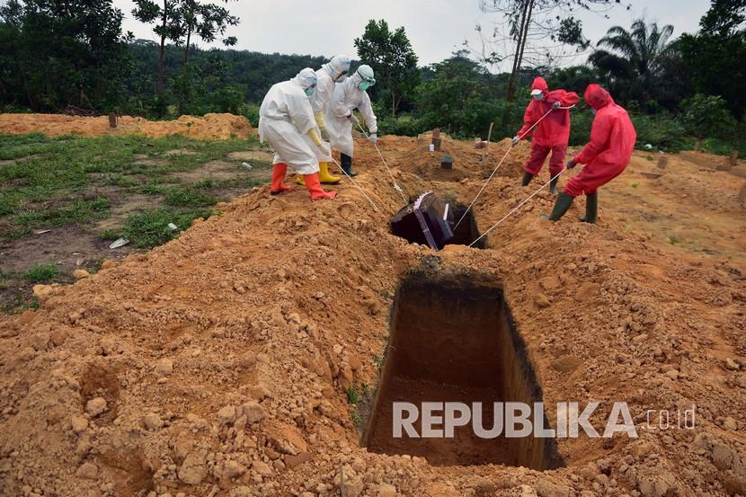 Sejumlah tenaga kesehatan dan penggali kubur mengenakan alat pelindung diri saat proses pemakaman jenazah dengan protokol kesehatan Covid-19 di Tempat Pemakaman Umum (TPU) Tengku Mahmud Palas, Kota Pekanbaru, Riau.
